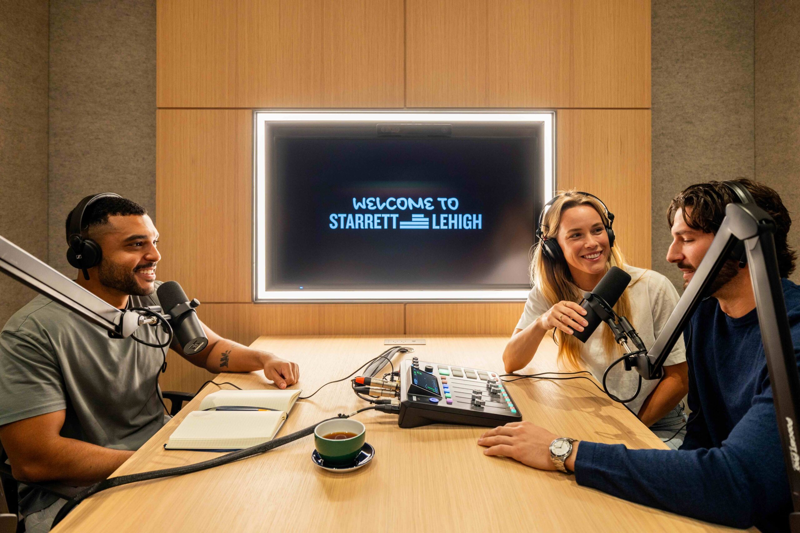 Three people recording a podcast with microphones, headphones and a screen reading “welcome to starrett lehigh".