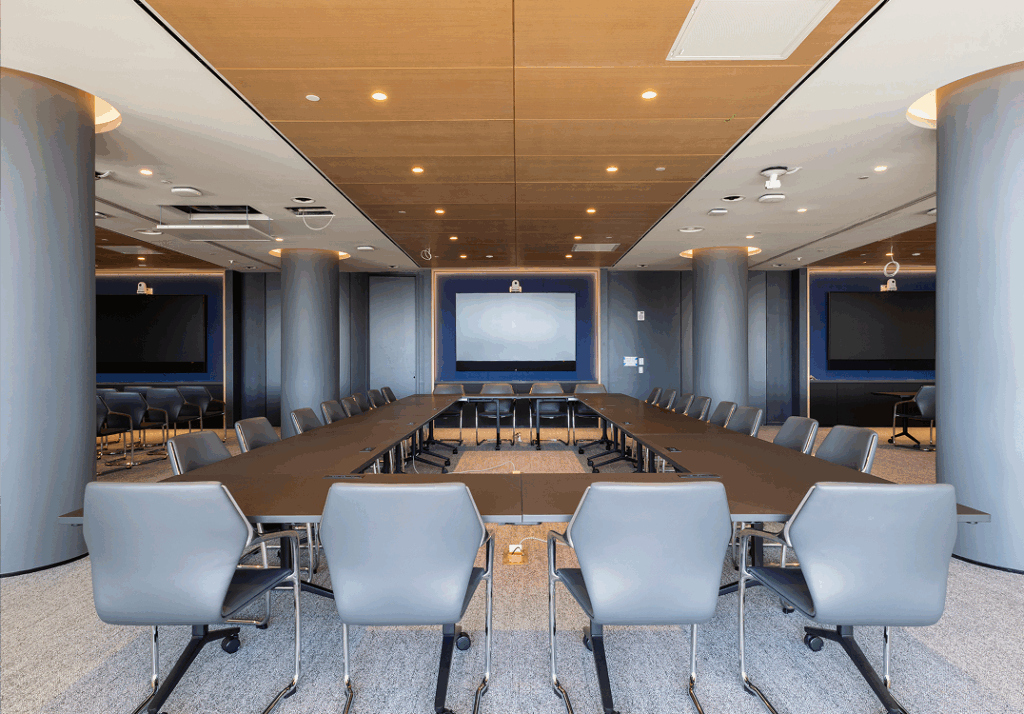 U-shaped conference room at level10 with gray chairs, screen, and wood-paneled ceiling.