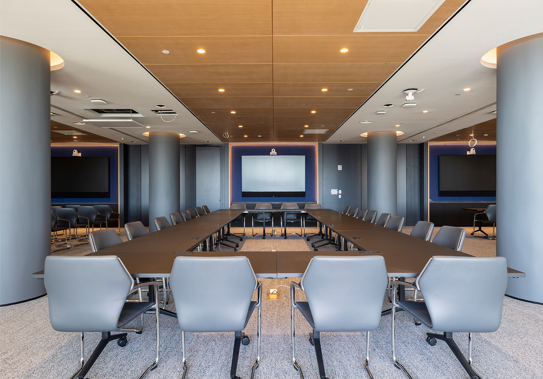U-shaped conference room at level10 with gray chairs, screen, and wood-paneled ceiling.