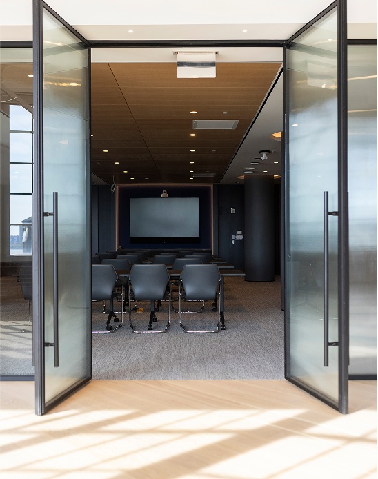 View through glass doors into level10 conference room with gray chairs and screen setup.