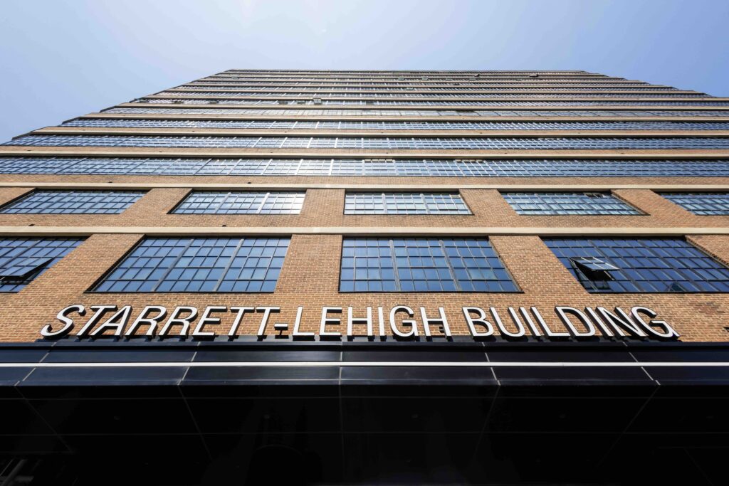 Starrett-lehigh building exterior with brick facade and grid windows, viewed from below against a clear blue sky in nyc.
