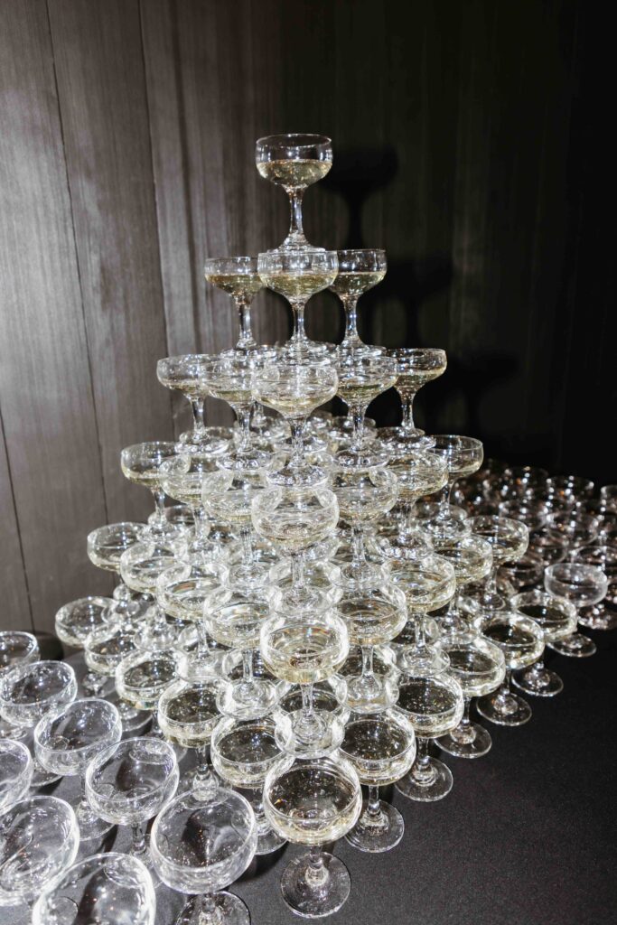 Champagne tower with cascading bubbles, elegantly stacked glasses glowing under soft light, perfect for upscale celebrations.