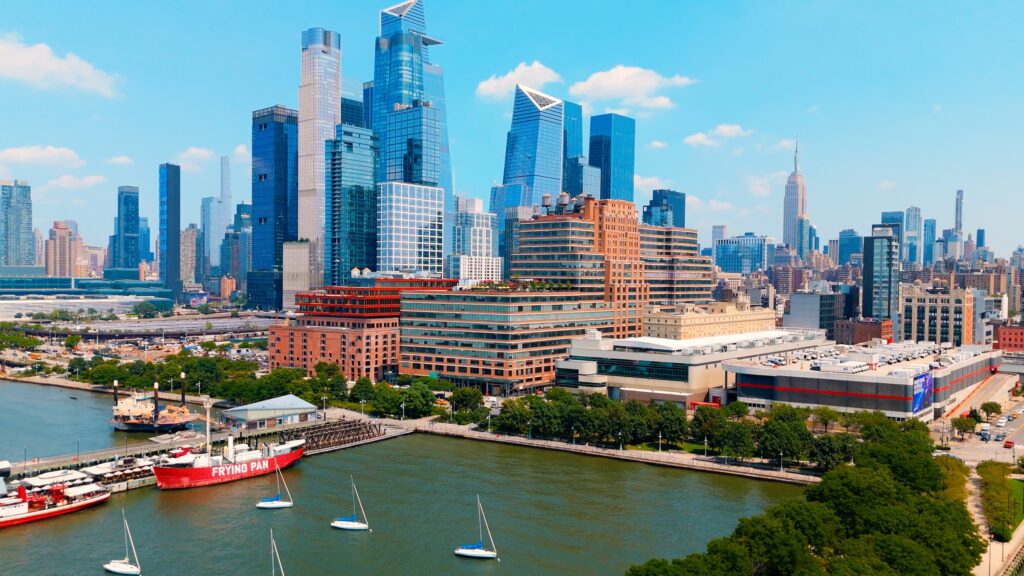 Manhattan skyline with modern skyscrapers, waterfront sailboats, and the red frying pan ship on the hudson river.