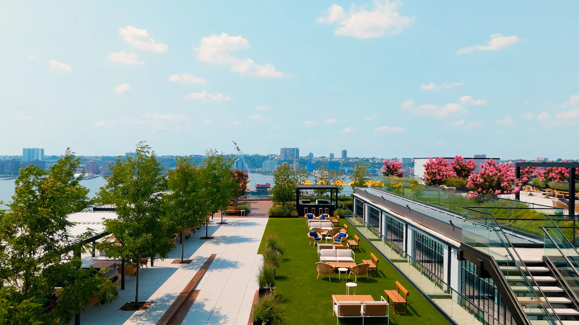 Drone view of level ten rooftop terrace in new york, featuring green spaces, seating areas, and cityscape in the background.