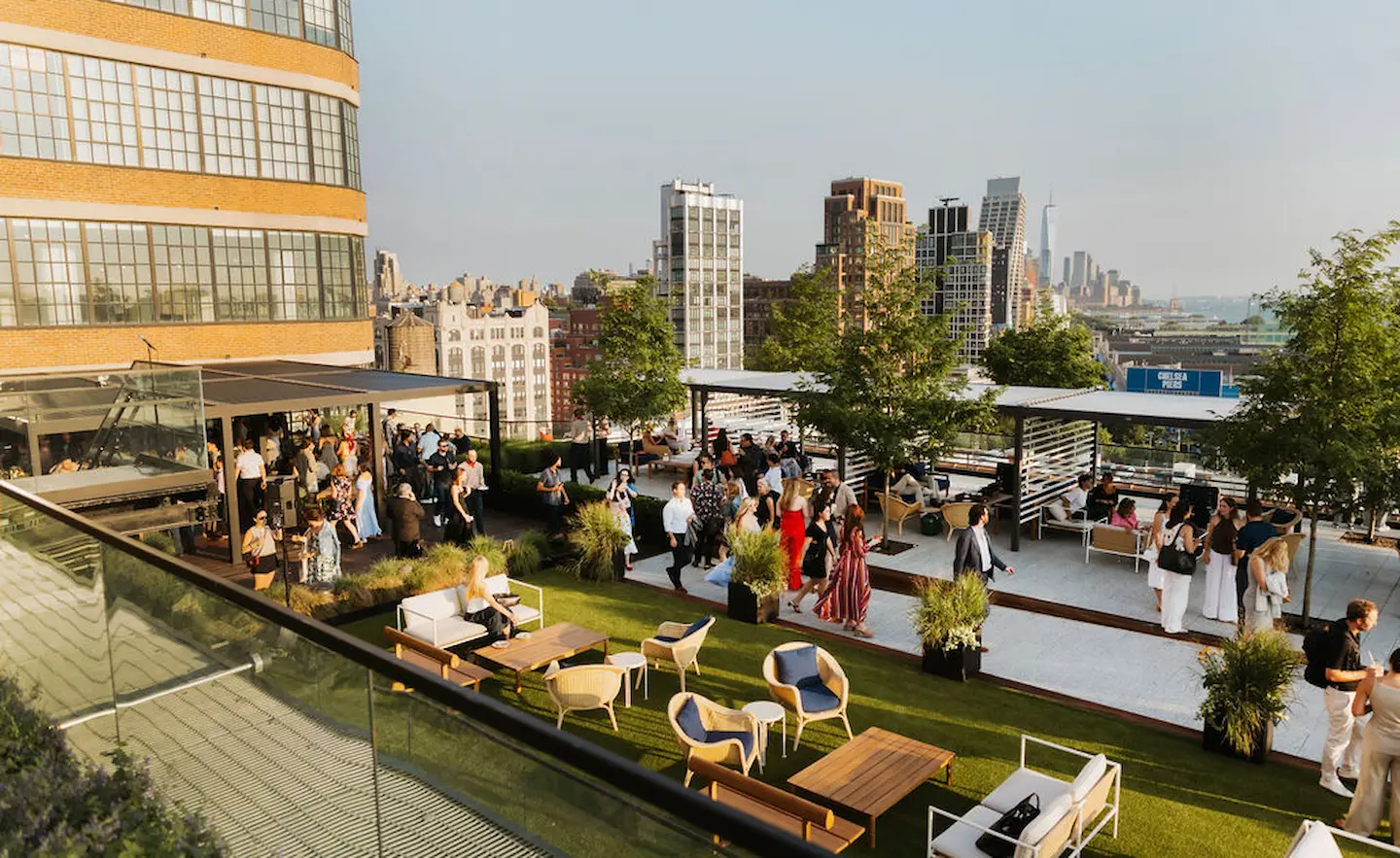 Stylish rooftop event with modern seating, city views, and guests mingling under pergolas on a sunny urban afternoon.
