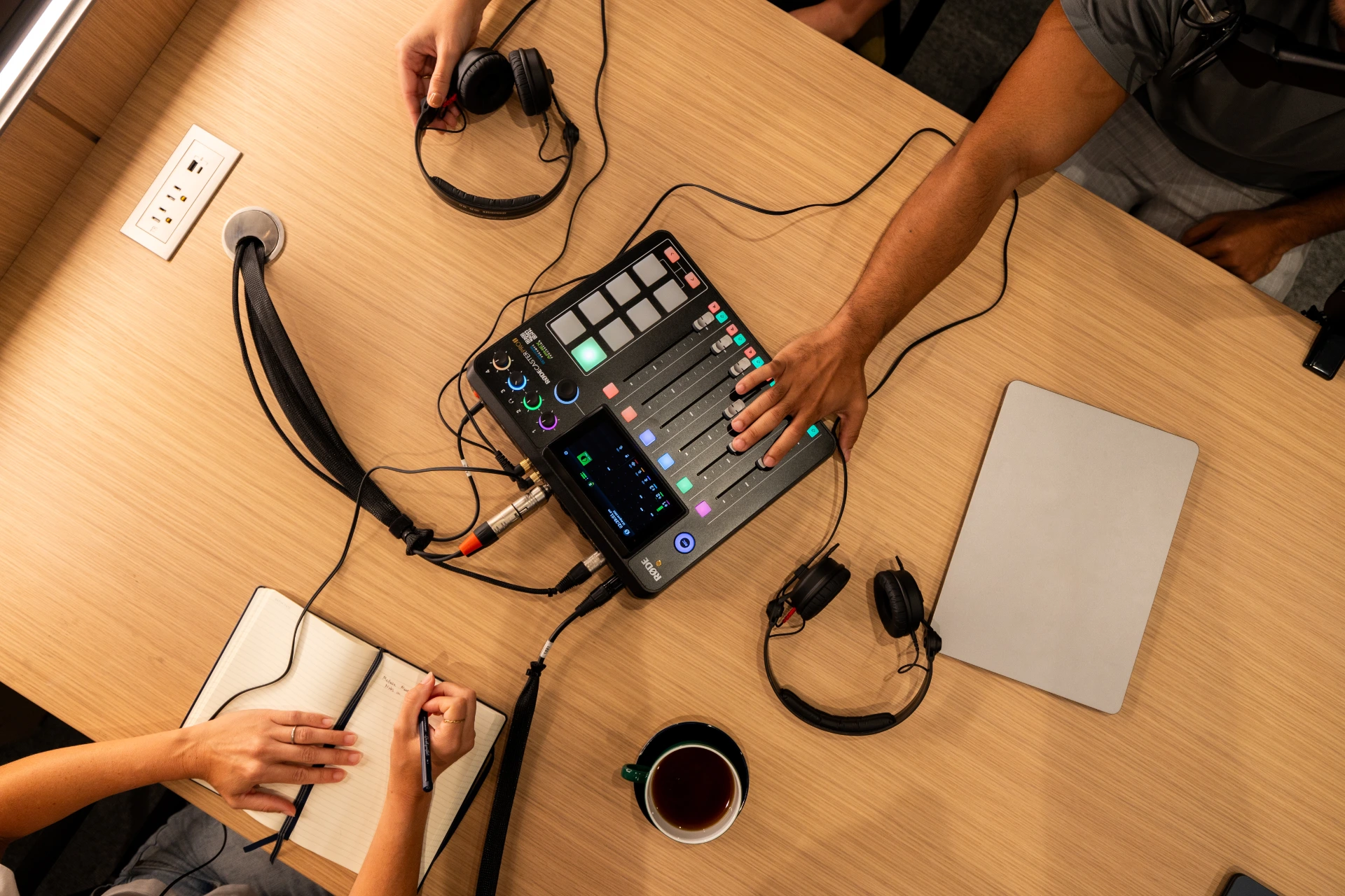 Overhead view of podcast production equipment, headphones, notebooks, and coffee setup inside level ten nyc’s media studio