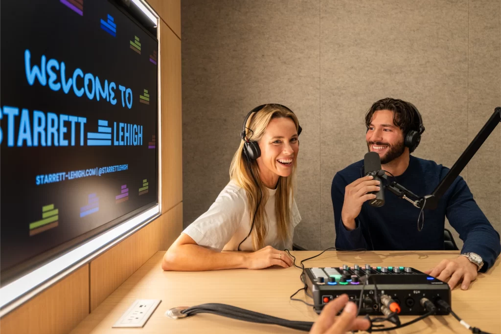 Podcast recording studio at level ten nyc with professional microphones, headphones, and branded presentation screen during a live recording session